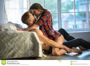 passionate-couple-kissing-boy-girl-sitting-wooden-floor-near-rumpled-bed-opposite-window-63443714